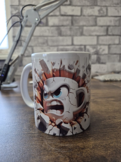Eine weiße Keramiktasse steht auf einer Holzoberfläche vor einer Backsteinwand. Auf der Tasse ist ein dynamisches Comic‑Motiv einer wütenden, animierten Kaffeetasse, die scheinbar durch eine aufgebrochene Wand bricht. Rechts im Hintergrund befindet sich e